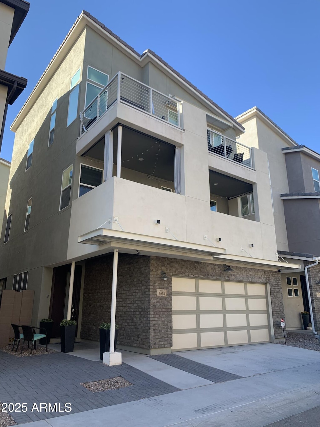 view of front of property featuring stucco siding, brick siding, concrete driveway, and a garage