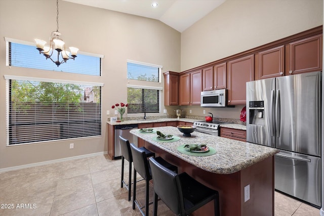 kitchen featuring a kitchen island, appliances with stainless steel finishes, pendant lighting, high vaulted ceiling, and a notable chandelier