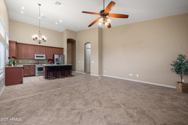 kitchen featuring a breakfast bar, a center island, appliances with stainless steel finishes, pendant lighting, and a towering ceiling