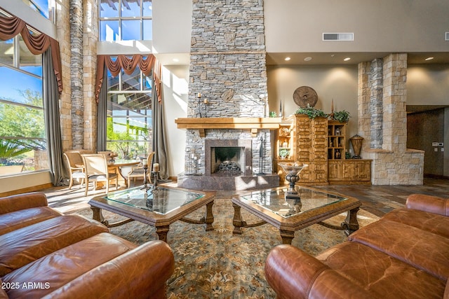 living room with hardwood / wood-style floors, a stone fireplace, ornate columns, and a high ceiling