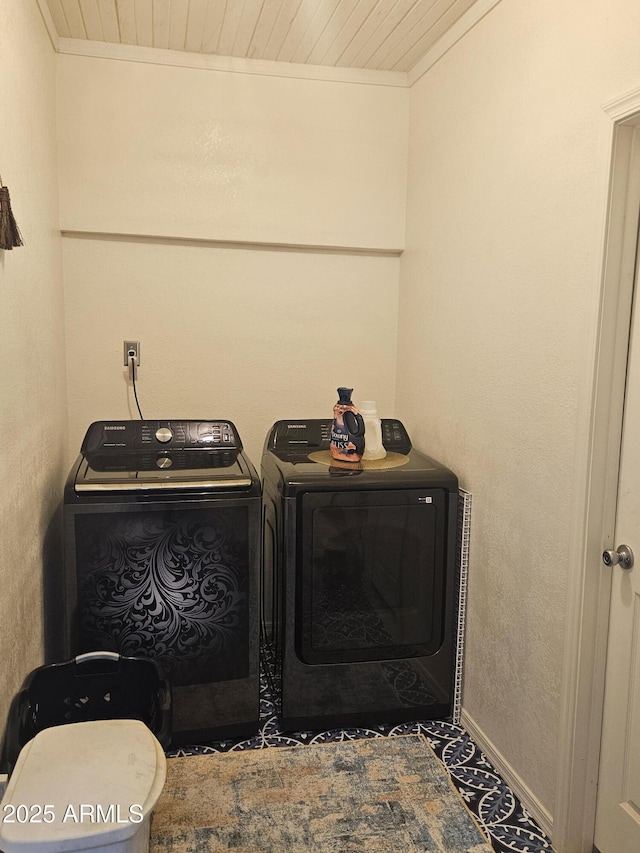 clothes washing area with washing machine and dryer, crown molding, and wood ceiling