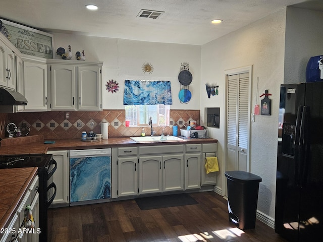 kitchen with dishwasher, white cabinetry, tile counters, sink, and black refrigerator with ice dispenser