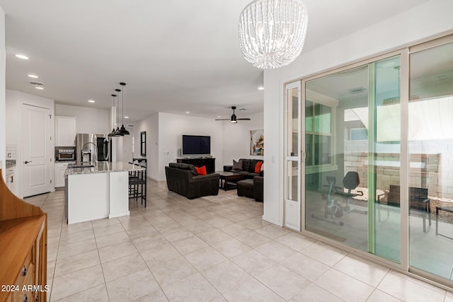 living room with light tile patterned floors and ceiling fan with notable chandelier