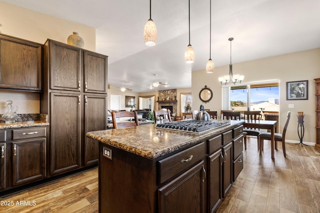 11180 E Navajo Dr, Dewey, AZ 86327 - kitchen with stainless steel gas stovetop, a fireplace, hardwood / wood-style flooring, and dark brown cabinets