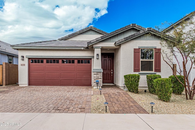 view of front facade featuring stucco siding, a tiled roof, decorative driveway, and a garage