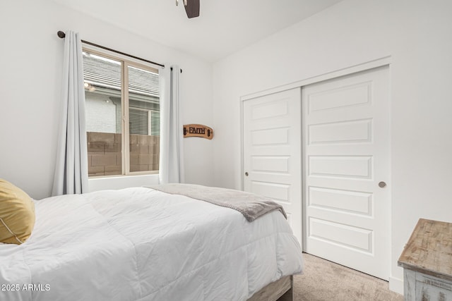 bedroom featuring a closet, light colored carpet, and a ceiling fan