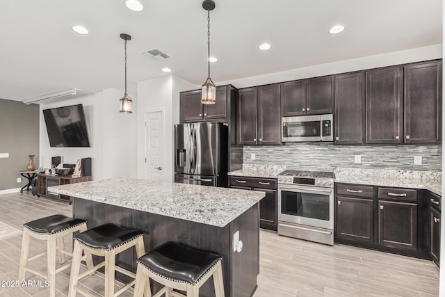 kitchen featuring tasteful backsplash, dark brown cabinets, a kitchen breakfast bar, and stainless steel appliances