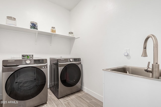 laundry area with baseboards, wood finish floors, laundry area, a sink, and washing machine and dryer