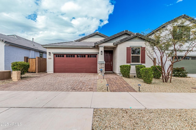 view of front facade with decorative driveway, a garage, stucco siding, and a tile roof