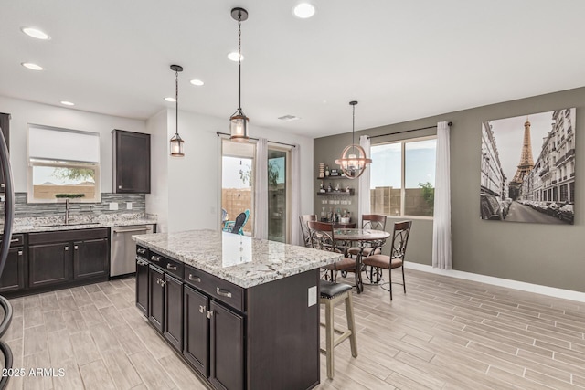 kitchen featuring baseboards, wood finish floors, a sink, decorative backsplash, and stainless steel dishwasher