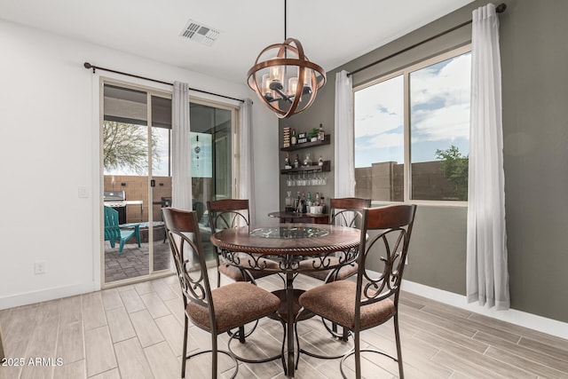 dining space with visible vents, baseboards, wood finish floors, a chandelier, and a dry bar