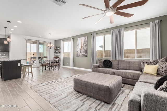 living room featuring baseboards, visible vents, wood finish floors, recessed lighting, and ceiling fan with notable chandelier