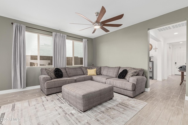 living room with visible vents, wood finish floors, baseboards, and a ceiling fan