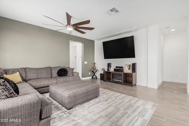 living area with visible vents, baseboards, a ceiling fan, and wood finished floors