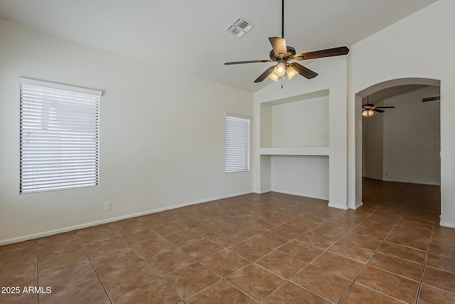 tiled spare room featuring built in features, visible vents, ceiling fan, arched walkways, and lofted ceiling