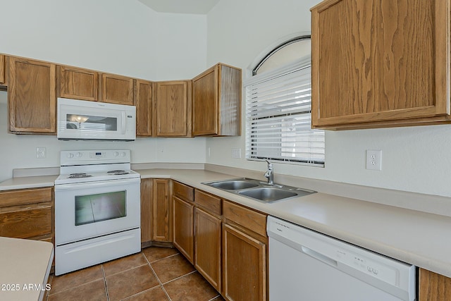 kitchen with white appliances, light countertops, a sink, and dark tile patterned floors