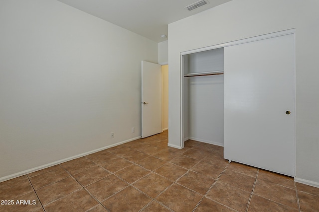 unfurnished bedroom with tile patterned floors, a closet, visible vents, and baseboards