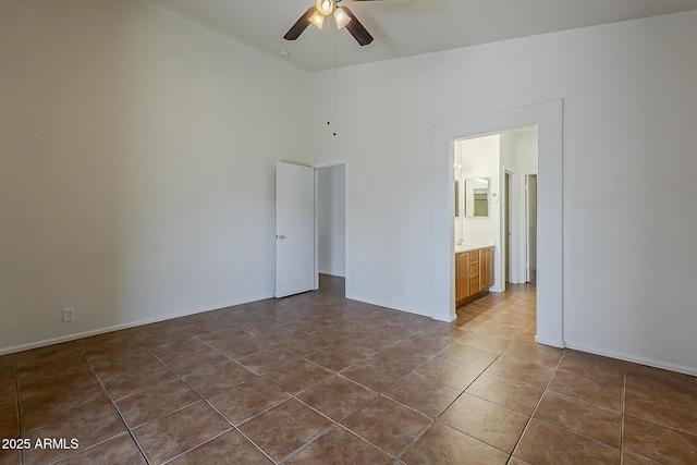 unfurnished bedroom featuring dark tile patterned floors, a ceiling fan, high vaulted ceiling, ensuite bathroom, and baseboards