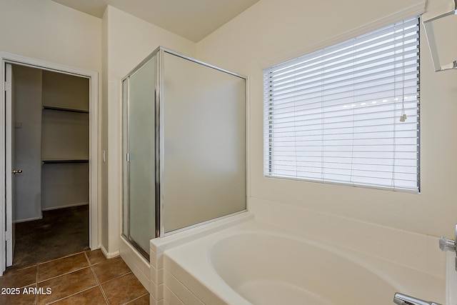 bathroom featuring a shower stall, tile patterned floors, a garden tub, and a walk in closet