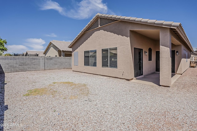 rear view of house featuring a fenced backyard, a patio, and stucco siding
