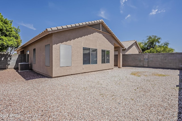 rear view of house featuring stucco siding, a tiled roof, and a fenced backyard