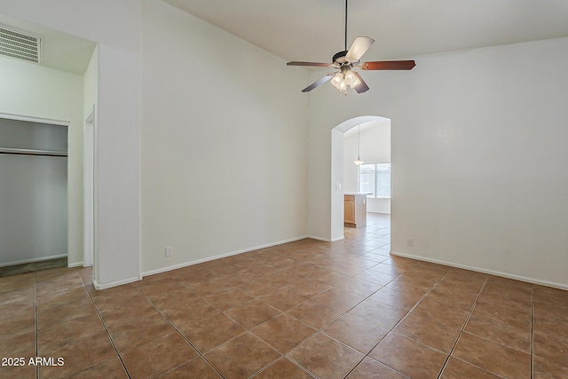 tiled empty room with baseboards, visible vents, ceiling fan, high vaulted ceiling, and arched walkways
