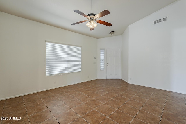tiled spare room with lofted ceiling, a ceiling fan, and visible vents