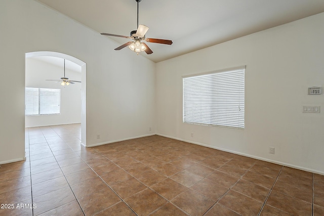 unfurnished room with a ceiling fan, lofted ceiling, tile patterned flooring, and arched walkways