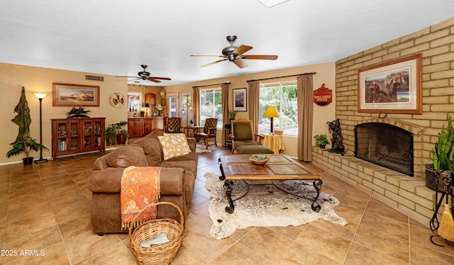 living area featuring a fireplace, visible vents, ceiling fan, and light tile patterned floors