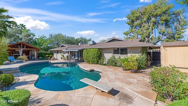 outdoor pool with a diving board, a gazebo, and a patio area