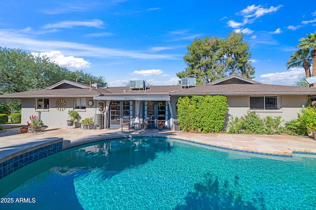 back of house featuring french doors, an outdoor pool, central air condition unit, and a patio area