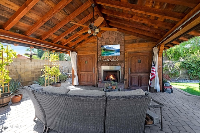 view of patio featuring an outdoor stone fireplace, fence, and a ceiling fan
