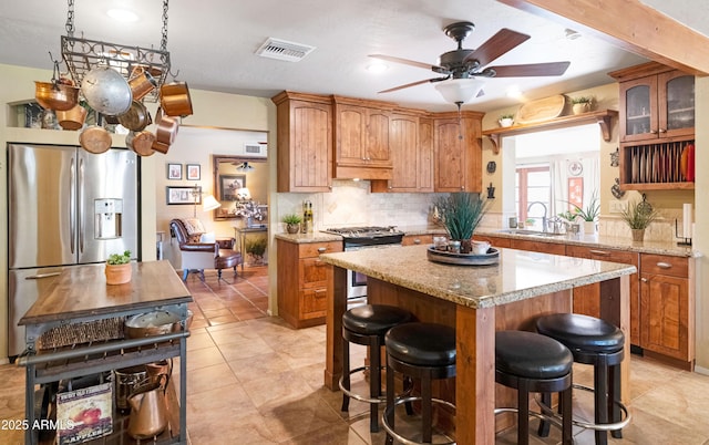 kitchen featuring a sink, backsplash, a breakfast bar area, appliances with stainless steel finishes, and visible vents