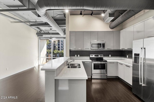 kitchen featuring pendant lighting, sink, tasteful backsplash, dark wood-type flooring, and appliances with stainless steel finishes