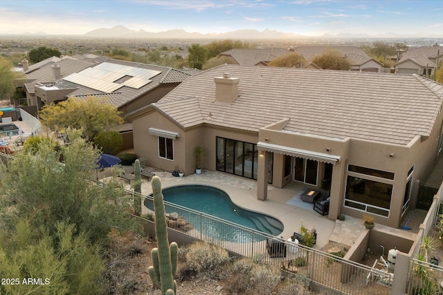 rear view of property with a fenced in pool, a mountain view, and a patio area