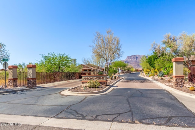 7617 E Desert Honeysuckle Dr, Gold Canyon, AZ 85118 - view of asphalt road with curbs, a mountain view, a gated entry, and traffic signs