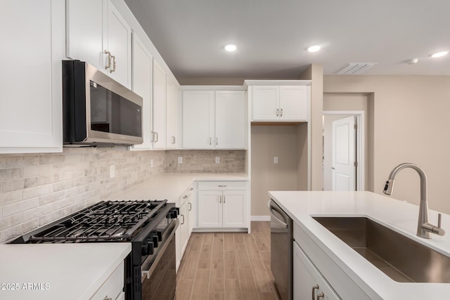5656 N 205th Ln, Buckeye, AZ 85396 - kitchen featuring appliances with stainless steel finishes, a sink, decorative backsplash, white cabinetry, and light wood-style flooring