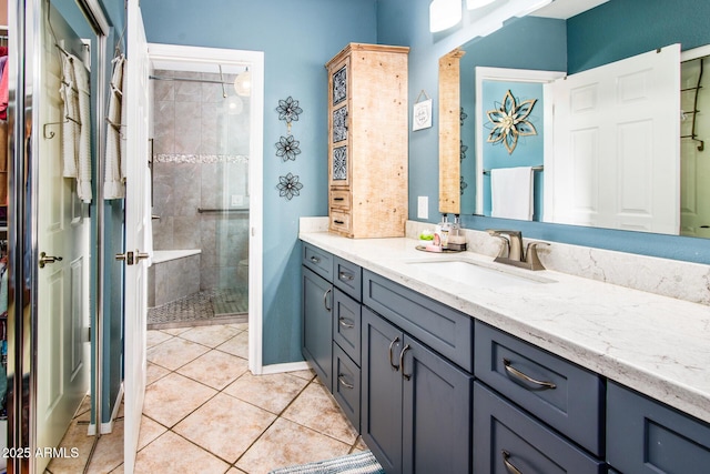 bathroom featuring tile patterned floors, baseboards, a stall shower, and vanity