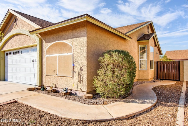 view of property exterior featuring stucco siding, driveway, a shingled roof, and a garage