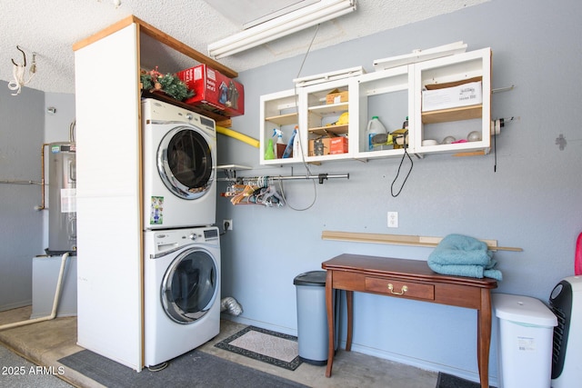 clothes washing area featuring a textured ceiling, laundry area, water heater, and stacked washing maching and dryer