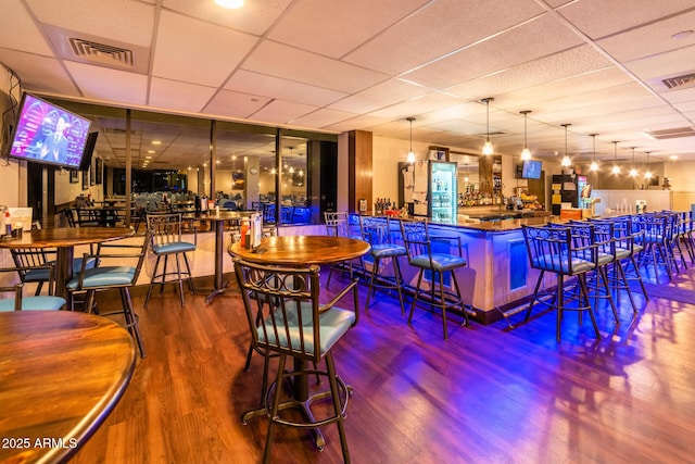 bar featuring a community bar, visible vents, a paneled ceiling, and wood finished floors