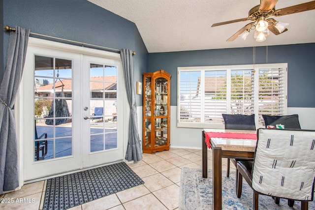 tiled dining area featuring ceiling fan, french doors, a textured ceiling, and lofted ceiling