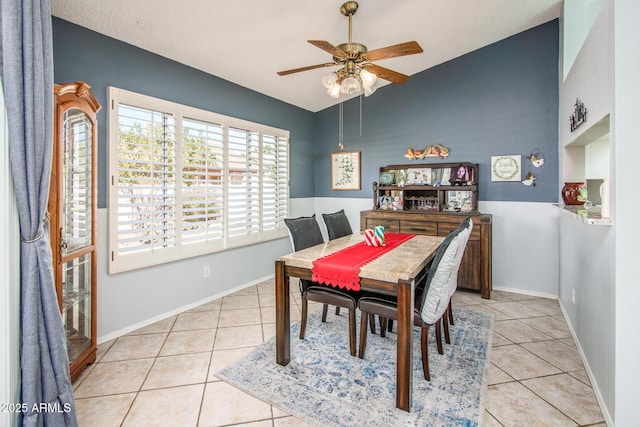 dining area featuring vaulted ceiling, light tile patterned flooring, a ceiling fan, and baseboards