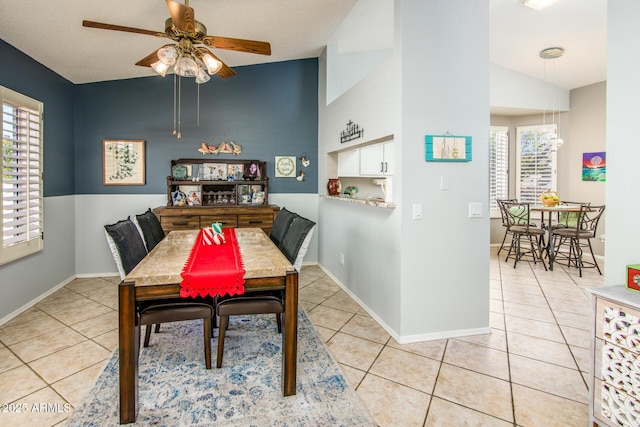 tiled dining space with baseboards, a ceiling fan, and vaulted ceiling