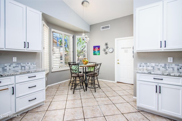 kitchen featuring light tile patterned floors, white cabinets, and backsplash