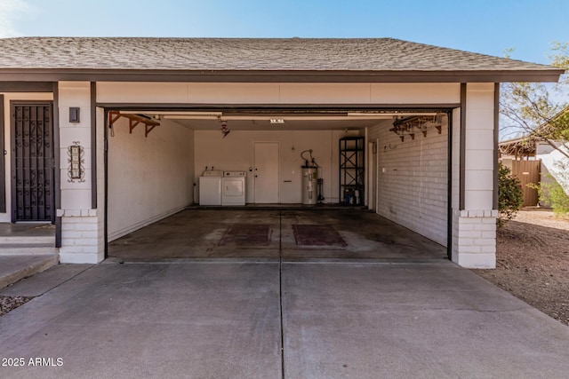 garage featuring driveway, water heater, and washing machine and clothes dryer