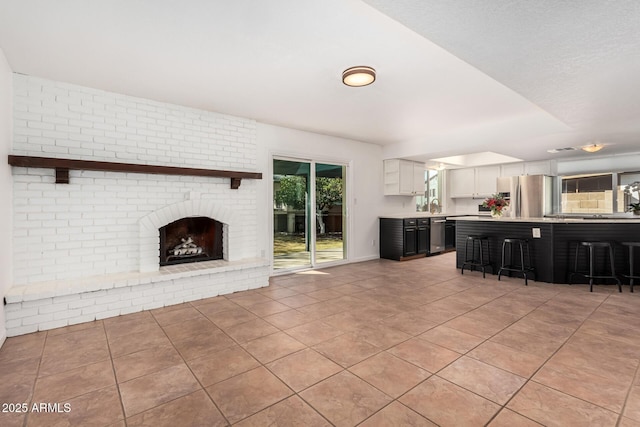 unfurnished living room with light tile patterned floors, a brick fireplace, and a sink