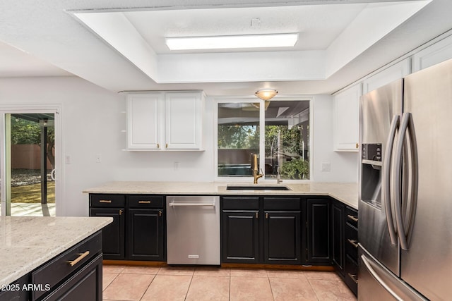 kitchen featuring light tile patterned floors, stainless steel fridge, white cabinets, dark cabinets, and a sink