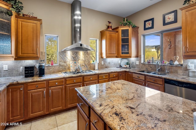 kitchen featuring appliances with stainless steel finishes, backsplash, light stone counters, sink, and wall chimney range hood