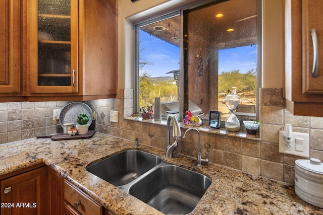 kitchen with backsplash, light stone countertops, and sink